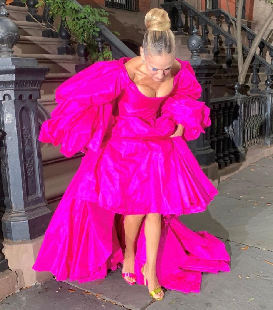 Sarah Jessica Parker on a New York street in bright pink dress and hair in a bun