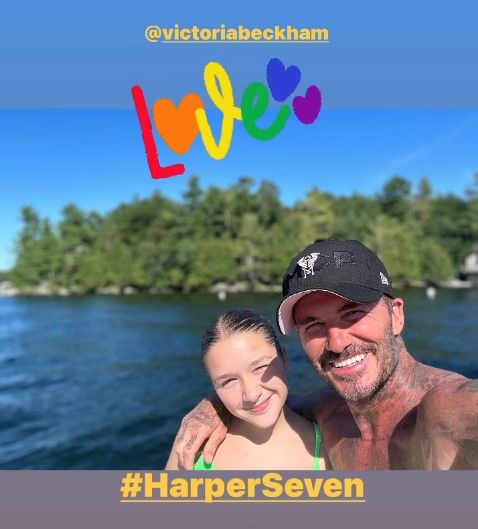 Harper and David Beckham smiling next to a lake