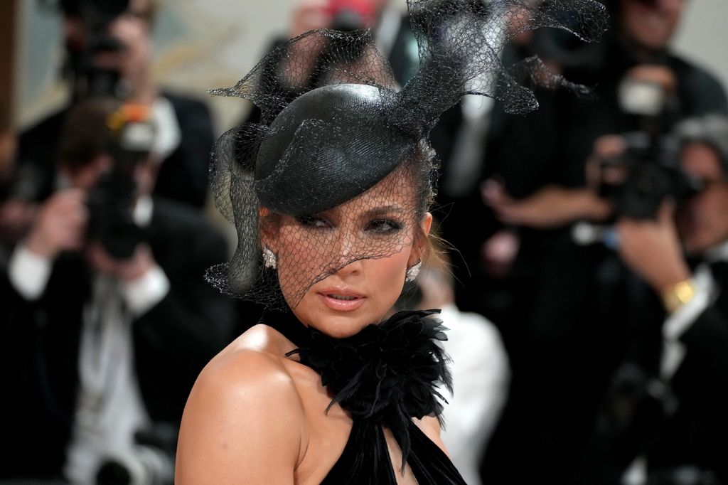 Jennifer Lopez looks over her shoulder as she styles elaborate fascinator at Met Gala 2023