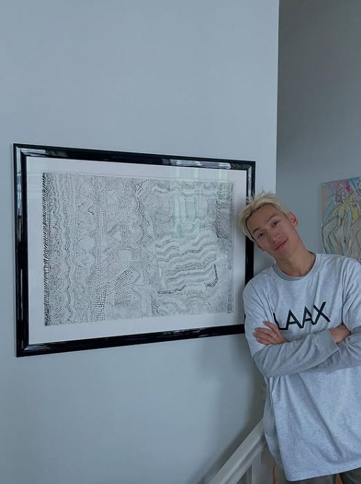 Carlos Gu standing next to a painting