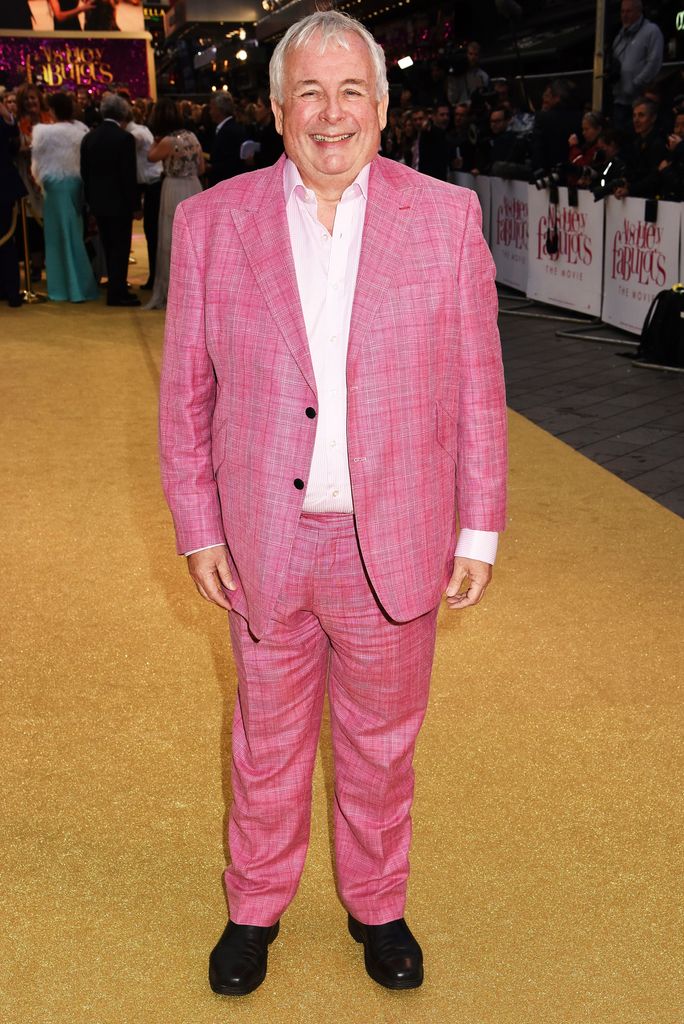 Christopher Biggins smiling in a pink suit and white shirt
