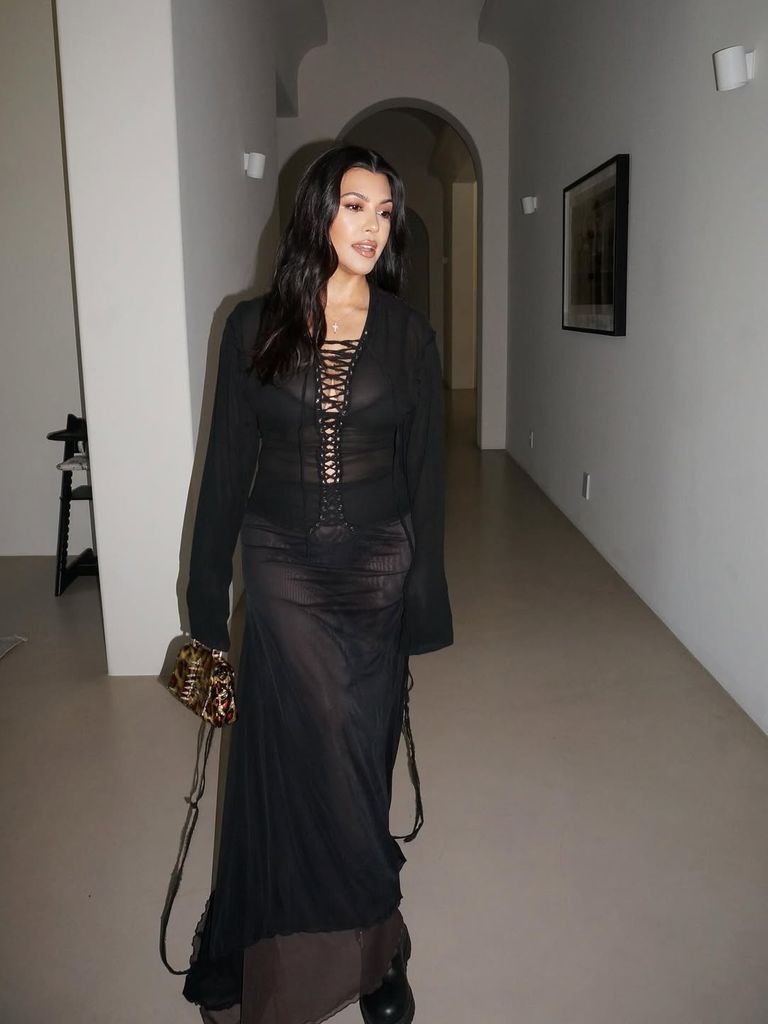 Kourtney Kardashian in long black dress walking through hallway