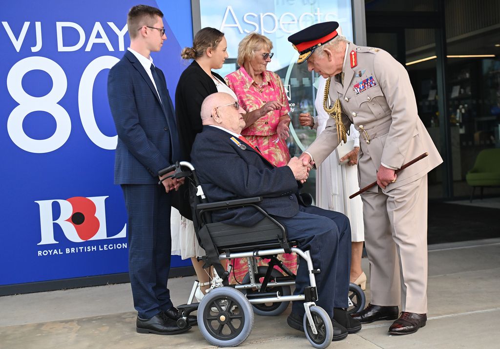 King Charles III talking to war veteran in wheelchair