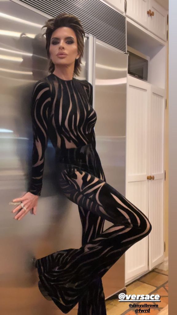 Lisa leaning against a wall and posing in the catsuit