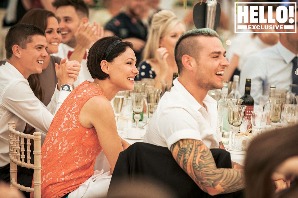 Emma Willis smiling at a table in an orange dress with Matt Willis