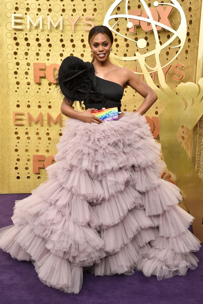 Laverne Cox wearing a dress, holding a rainbow clutch