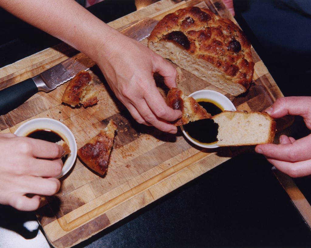 bread on wooden board and dipping oil in bowl