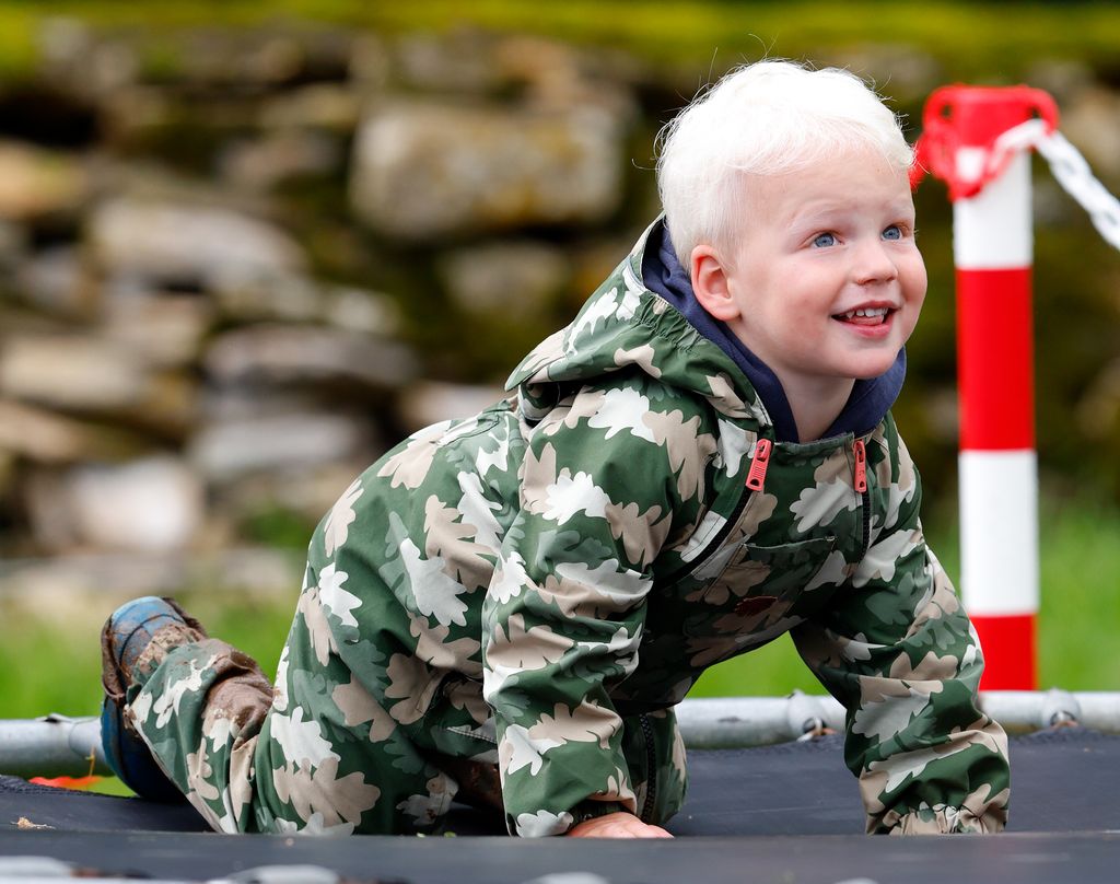 little boy on trampoline in puddlesuit 