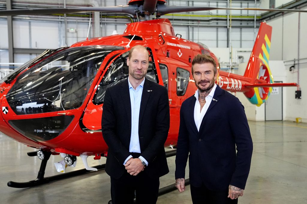 two men in suits standing in front of red helicopter