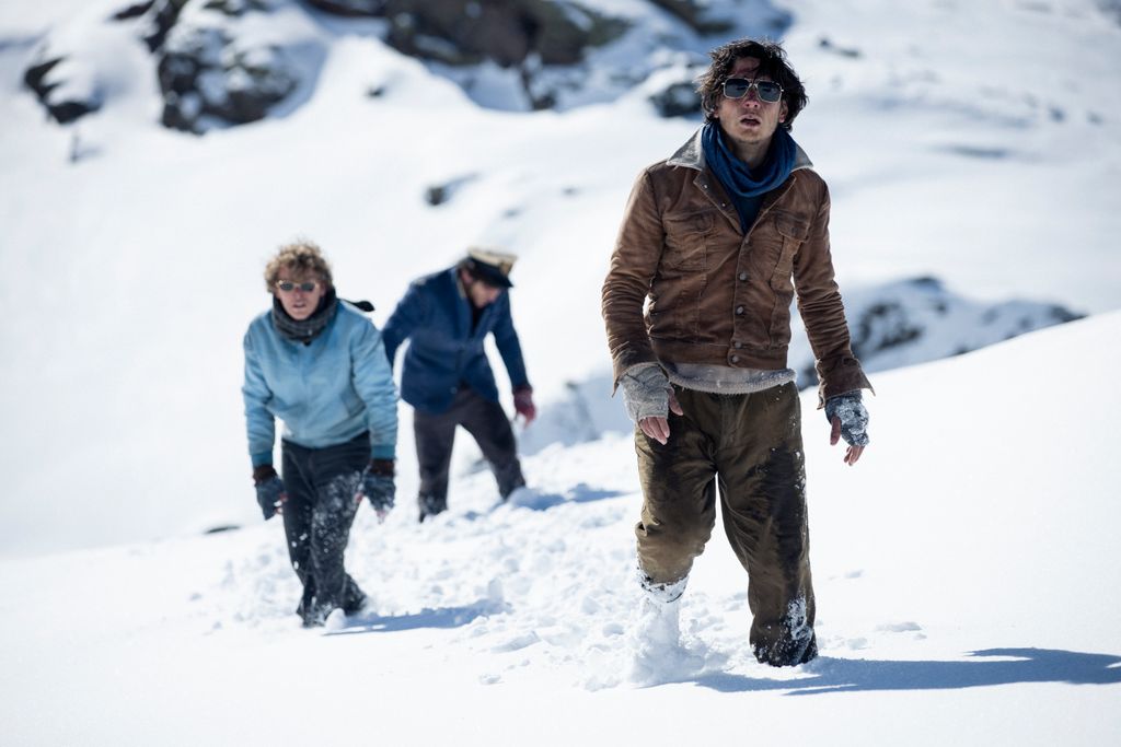 Three men walk through snow 