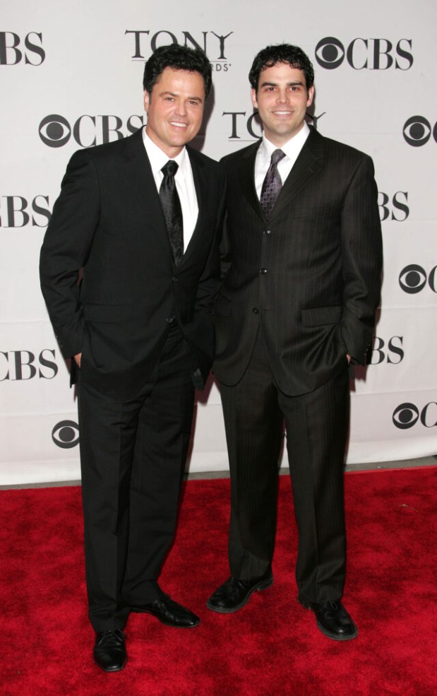Donny and Don Osmond stood next to eachother in suits smiling on the red carpet 