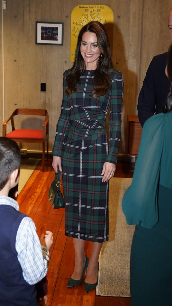 The Princess of Wales smiling in green tartan dress inside wooden building
