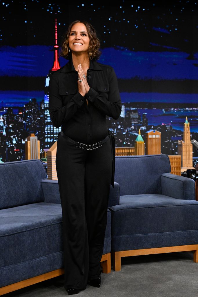 Halle Berry standing up in black outfit on talk show set