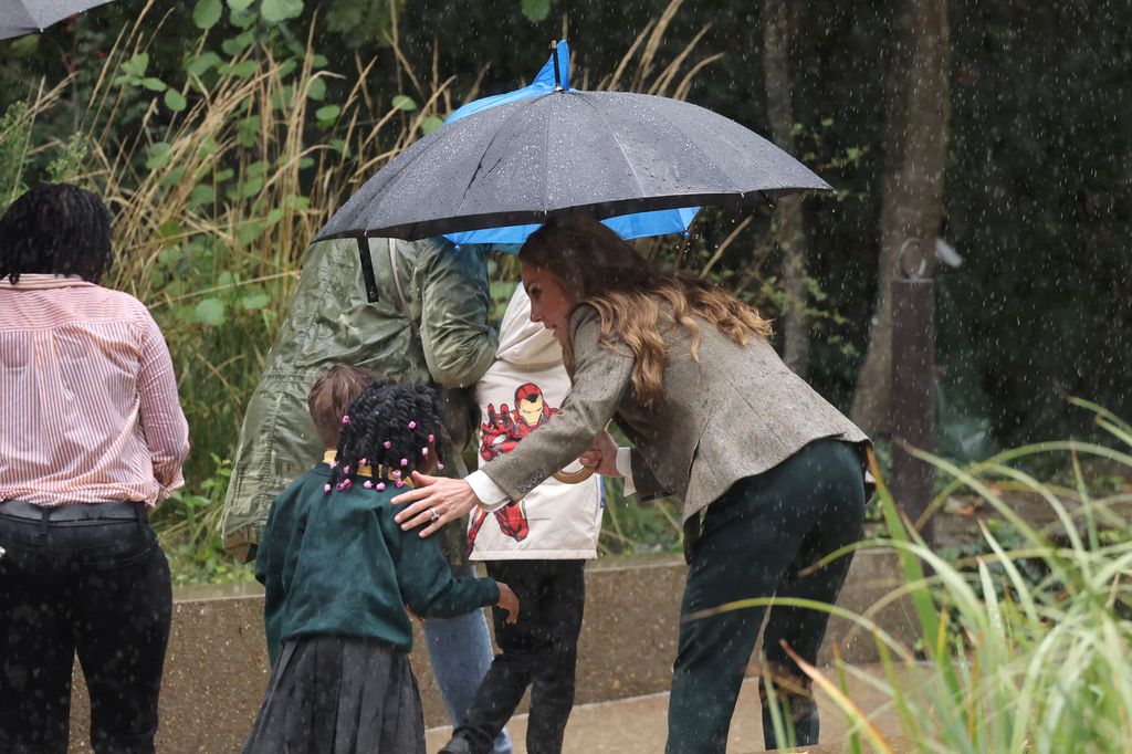 Kate Middleton underneath an umbrella with two children