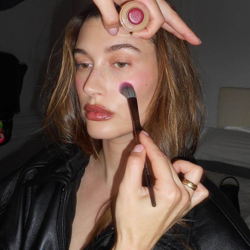 Hailey Bieber putting on Rhode blush 