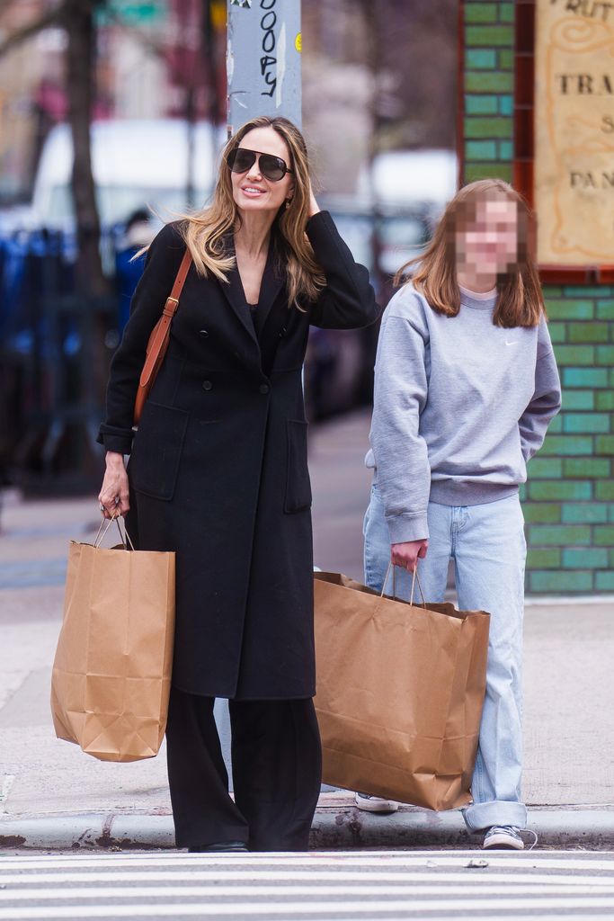 mother and daughter crossing road with brown shopping bags