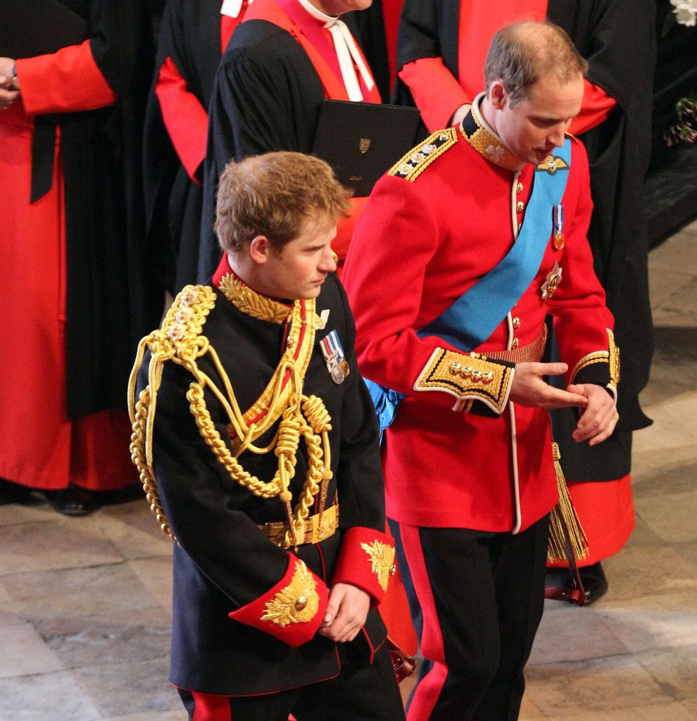 Prince Harry in his black military uniform and Prince William in his red military uniform