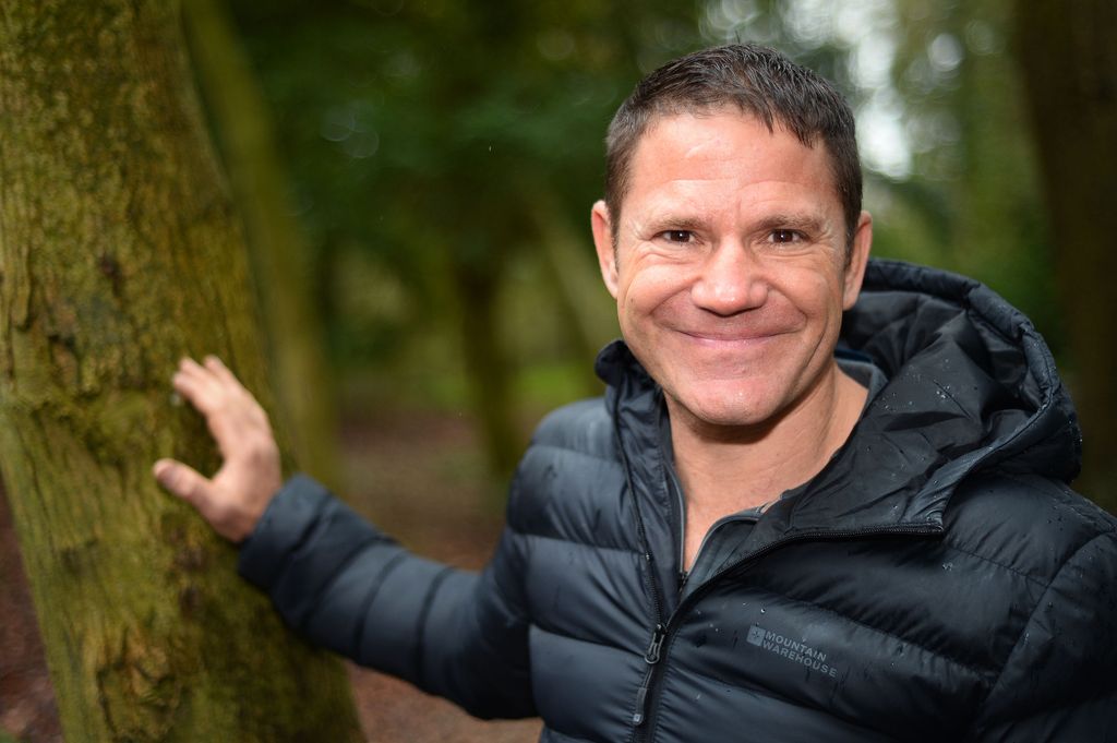 steve backshall with one hand on tree 