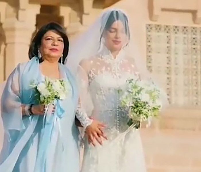 Priyanka Chopra in a wedding dress holding hands with her mum 