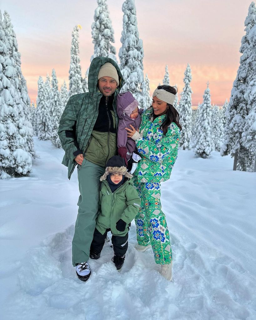 family of four posing in snow 