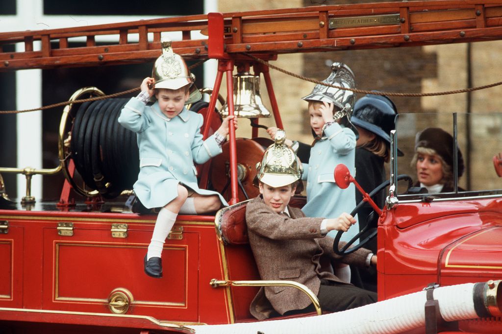 harry and william wearing blue coats whilst playing on fire engine 