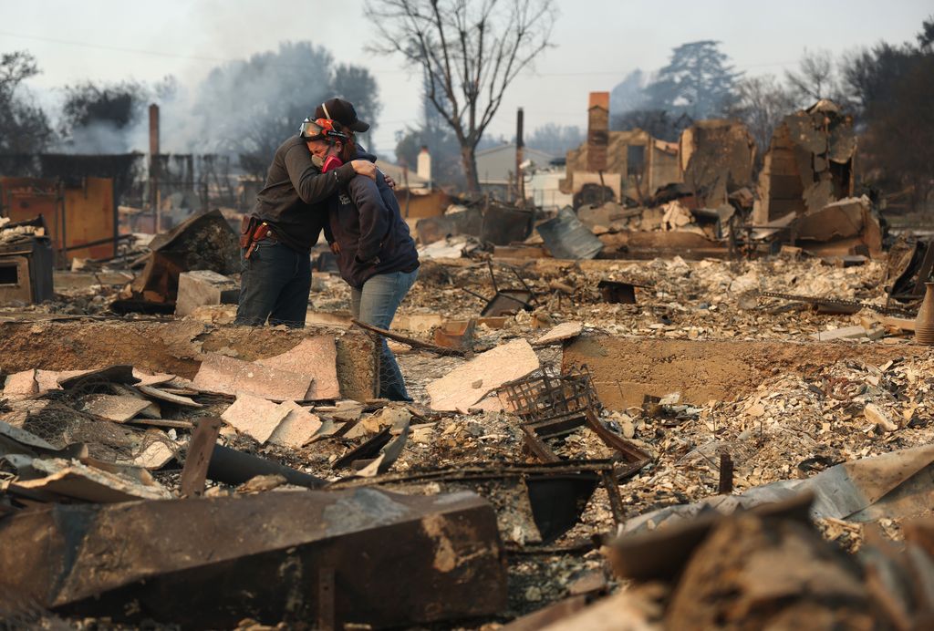 Khaled Fouad (L) and Mimi Laine (R) embrace as they inspect a family member's property that was destroyed by Eaton Fire on January 09, 2025 in Altadena, California