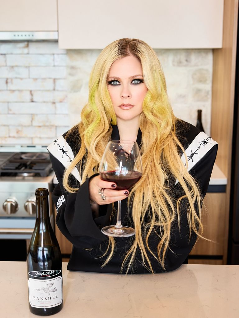 photo of avril lavigne holding a glass of wine in a kitchen