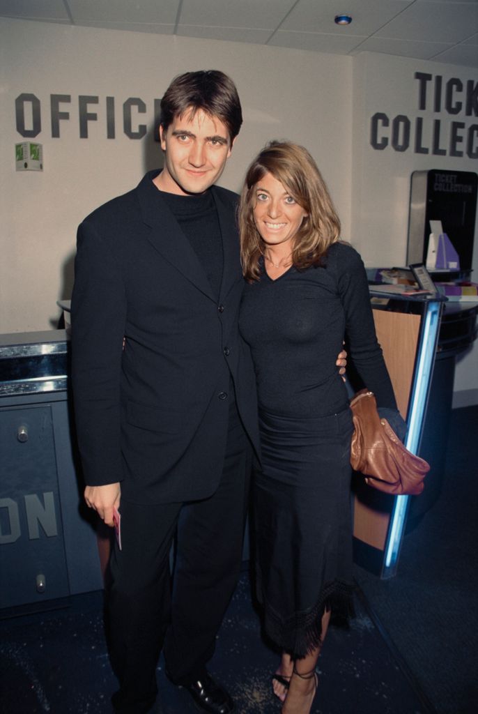 Kris Thykier in a blue suit with his arm around Claudia Winkleman, who wears a blue dress