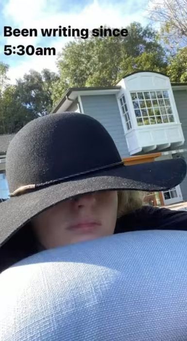 rebel wilson lying down with a black hat on