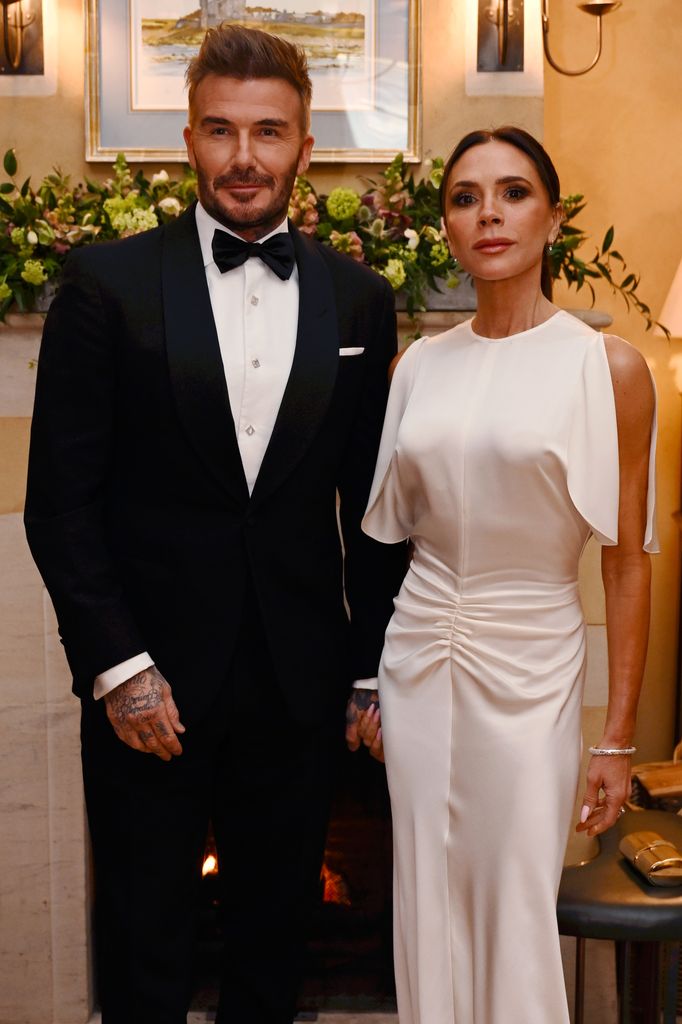 David Beckham in a tuxedo standing with Victoria Beckham in a white dress