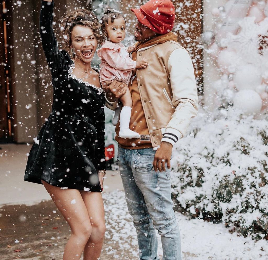 Nick Cannon holds his daughter in a snow storm as Alyssa Scott cheers next to them