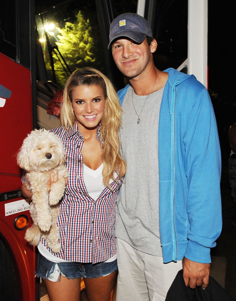 Jessica Simpson in stripe shirt holding dog with and Tony Romo in blue hoodie and cap in 2008 
