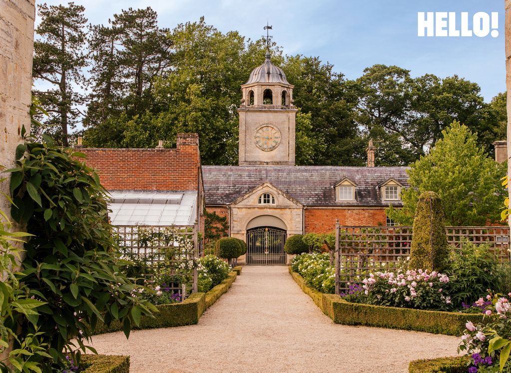 Les écuries du parc Buscot, avec une tour d'horloge qui sonne encore l'heure, entourées d'un jardin verdoyant
