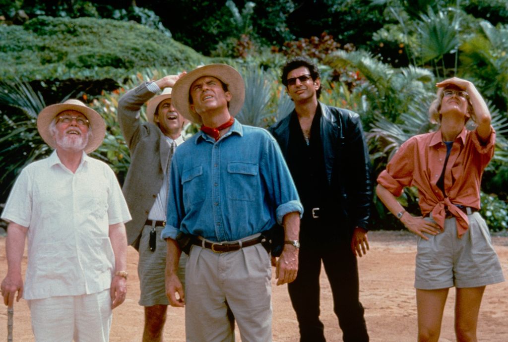 View of, from left, actors Richard Attenborough (in costume as John Hammond), Martin Ferrero (as Donald Gennaro), Sam Neill (as Alan Grant), Jeff Goldblum (as Ian Malcolm), and Laura Dern (as Ellie Sattler) in the film 'Jurassic Park' (directed by Steven Spielberg), 1993. (Photo by Murray Close/Moviepix/Getty Images)