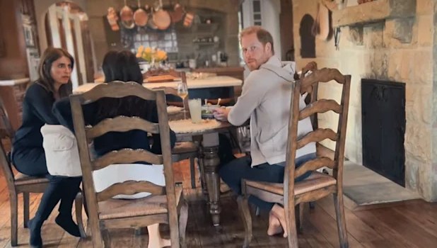 Prince harry looks at camera while sitting at dining table in their kitchen