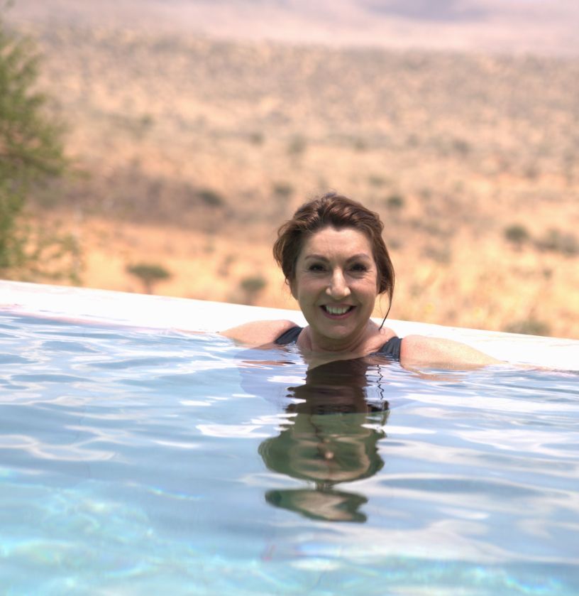 Jane McDonald in black swimsuit relaxing in swimming pool
