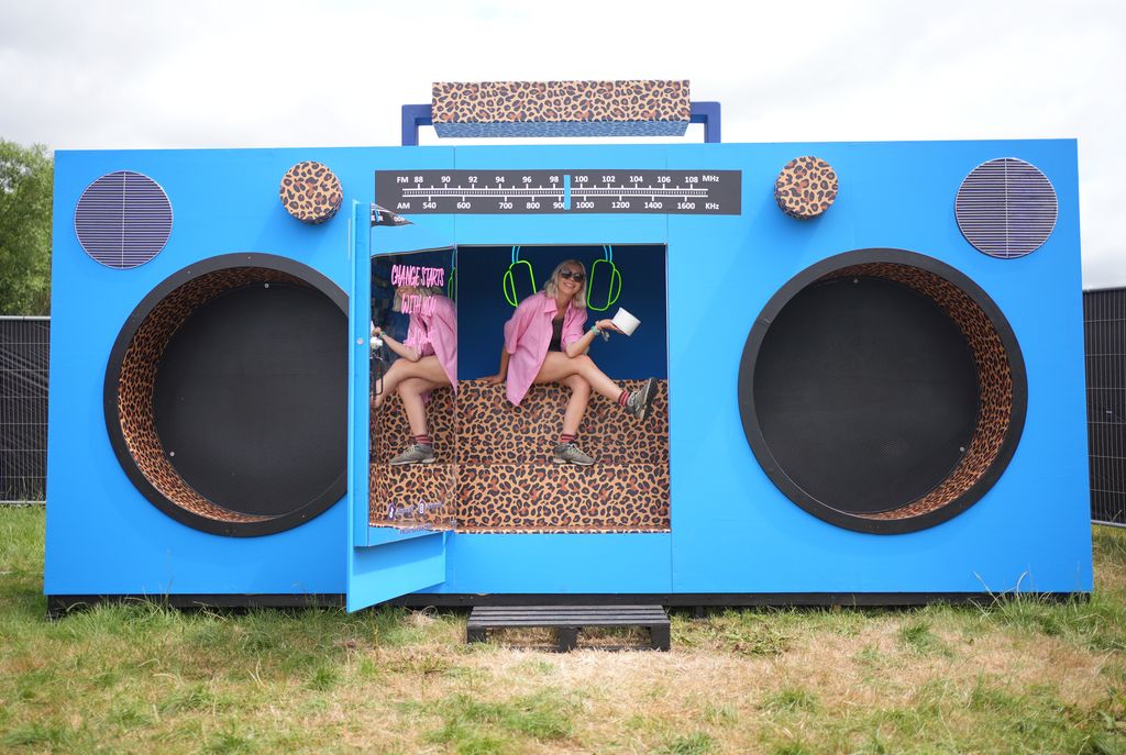 Un volontaire WaterAid pose à côté d'une tourbière dans une boombox - une toilette située derrière la bande de bande d'un boombox géant, co-conçue par Sir Rod Stewart et l'organisme de bienfaisance - situé près de la scène pyramide du Festival de Glastonbury