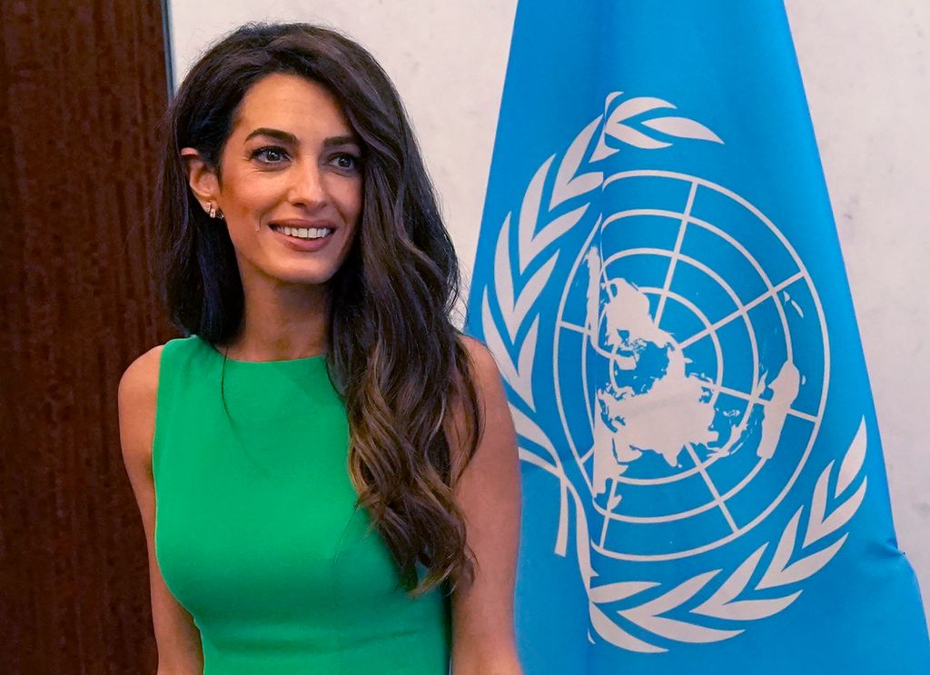Amal Clooney smiling in a green dress