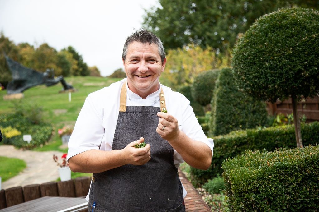 Chef holding herbs outside with golf course in background