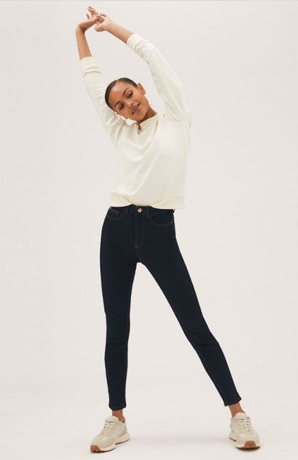 model standing in skinny jeans with her arms raised