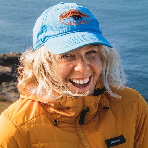 woman smiling in a cap against a sea backdrop