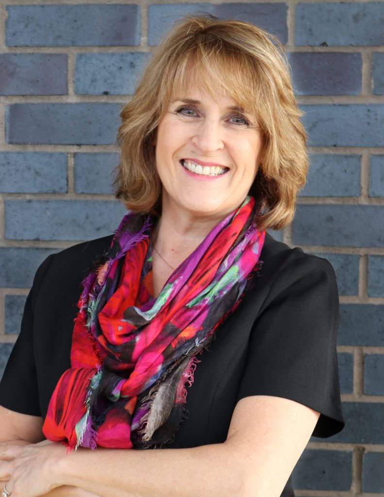 woman smiling in a colourful scarf and a black top