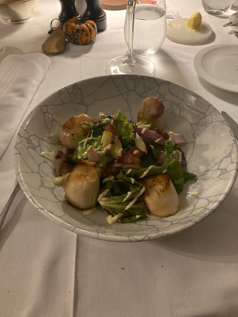 Bowl of scallops and salad on a table with a white tablecloth