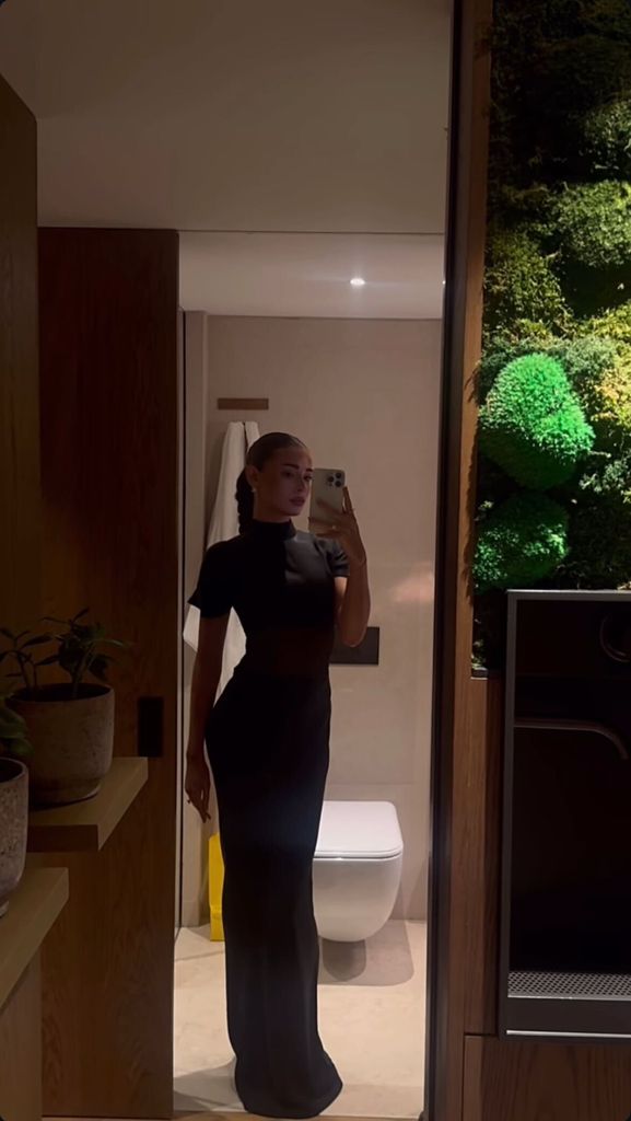 A photo of a woman wearing a brown dress in a hotel room