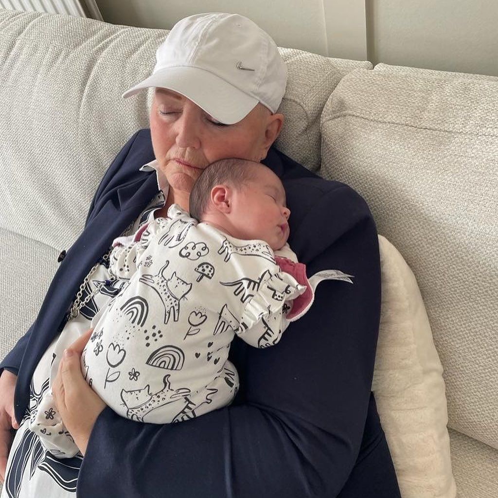 Linda Nolan asleep on a sofa cuddling a baby