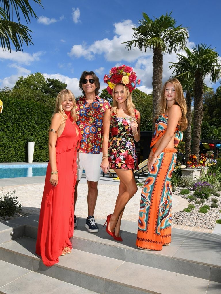 Amanda Holden with her husband, Chris, and their daughters Hollie and Lexi posing in smart clothes in front of a pool 