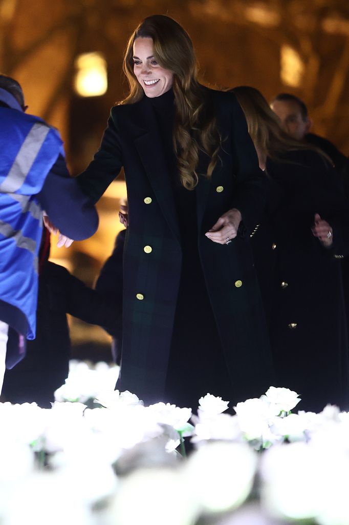 Kate Middleton shaking hands with a man while wearing a patterned coat