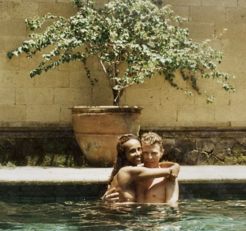 Iman and David Bowie hugging in a swimming pool