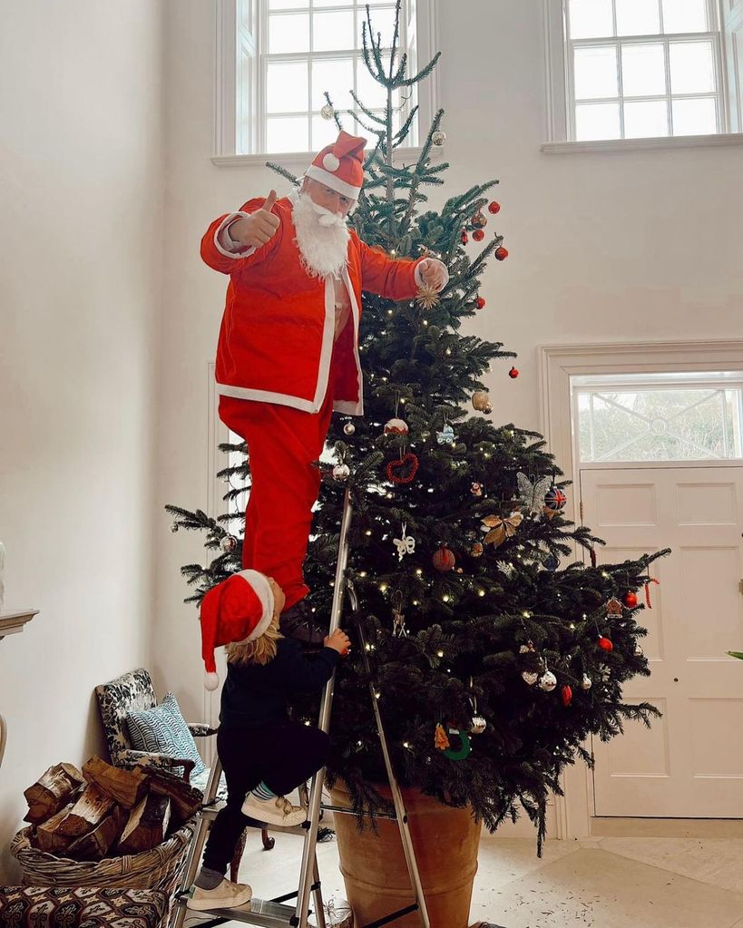 A photo of Boris Johnson dressed as santa decorating a Christmas tree 