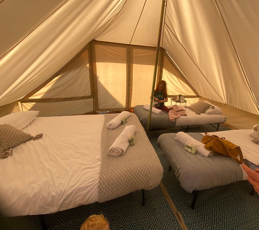The inside of a bell tent with double and single beds and little girl